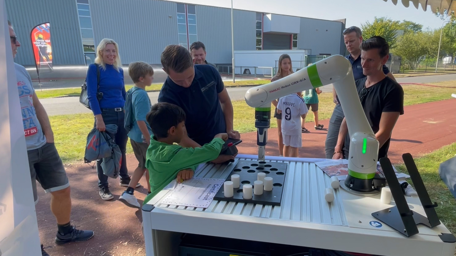 Kian Janssen-Groesbeek laat een jongetje zelf een Cobot demo robot besturen tijdens de Kies Techniek bedrijvendag in Venray