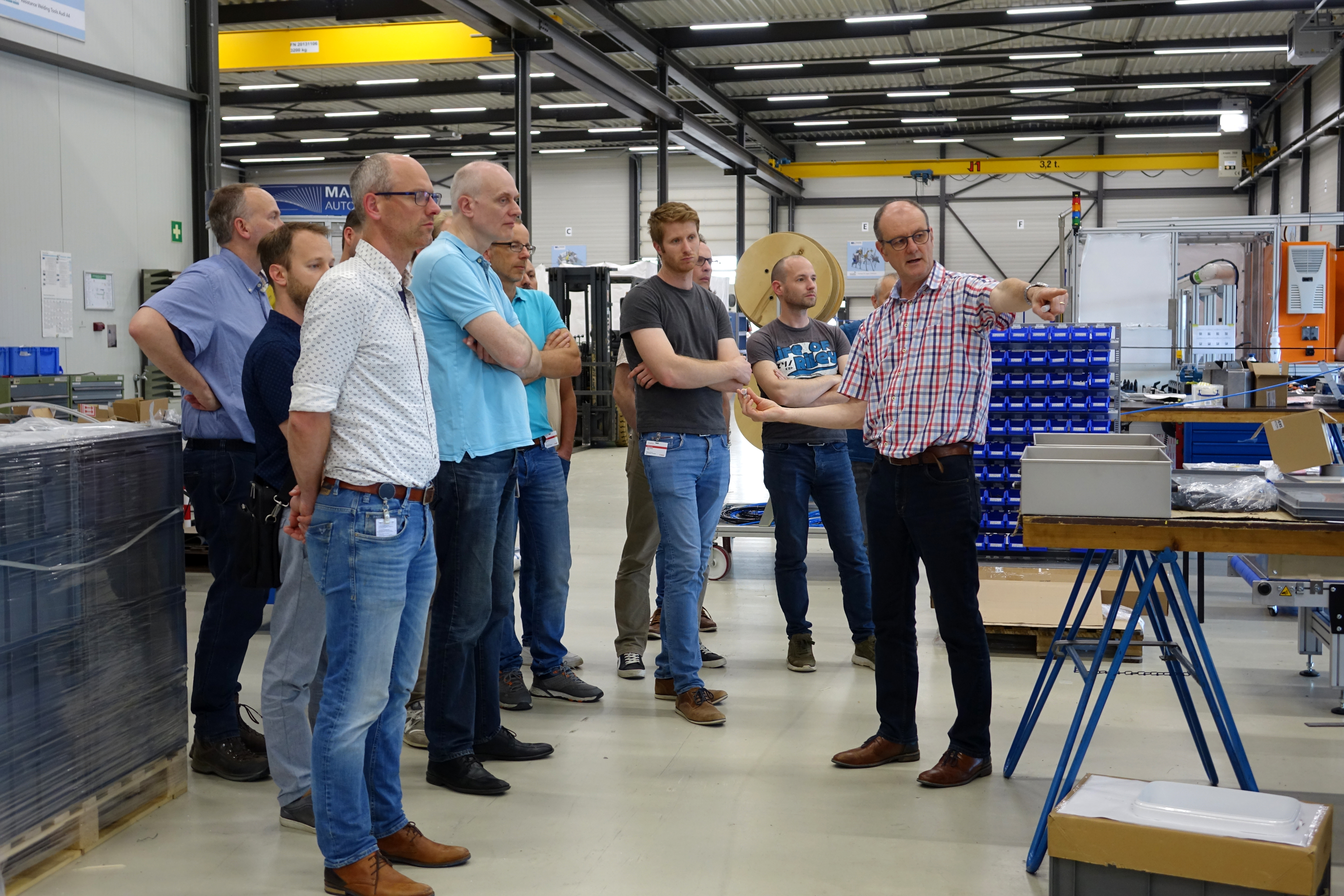 John Thijssen geeft bezoekers van Canon Production Printing uitleg bij Manders Automation en wijst naar een machine